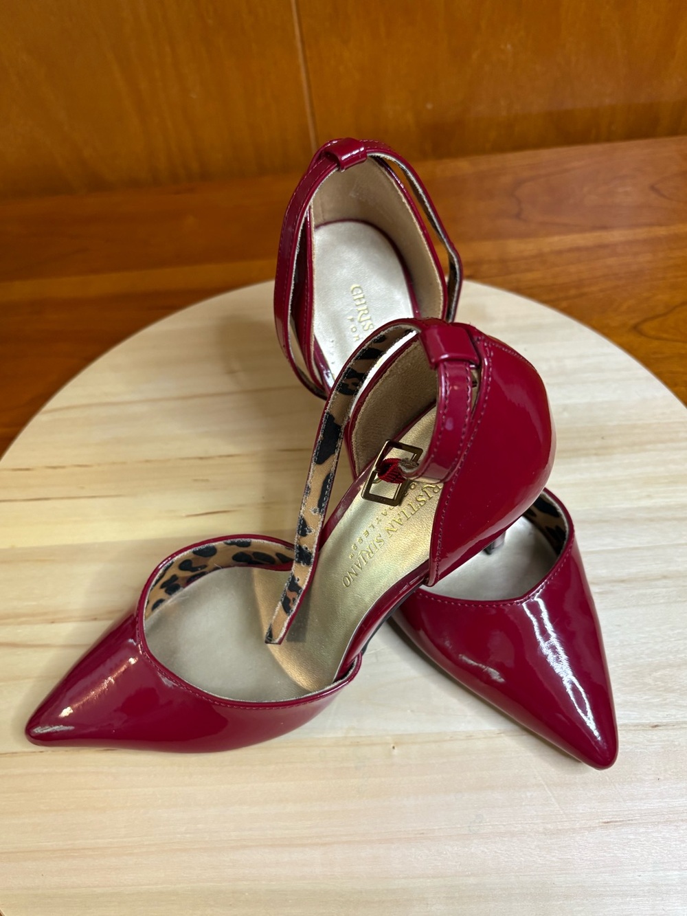 red patent ankle-strap pumps with a pointed toe and a striking cheetah inner